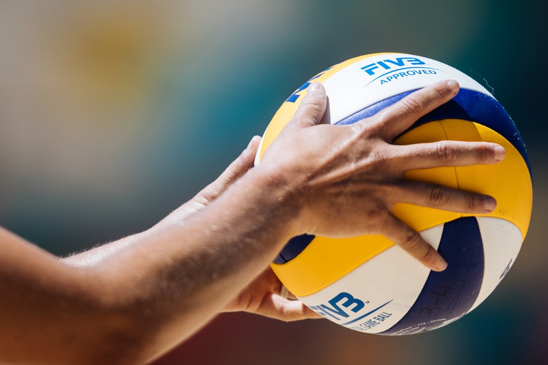 Eine Spielerin hält einen Beach-Volleyball in der Hand